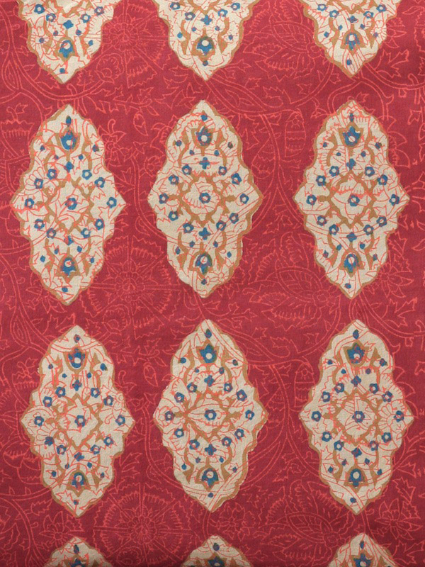 floral filigree of cinnamon, turmeric and imperial blue with motifs on a red orange ground