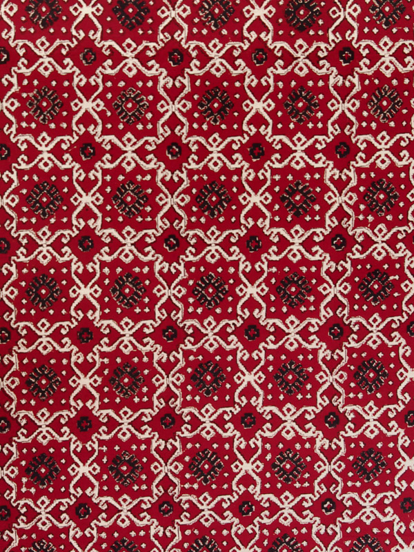 A bold dramatic black and tan kilim inspired geometrical print grounded in deep ruby red