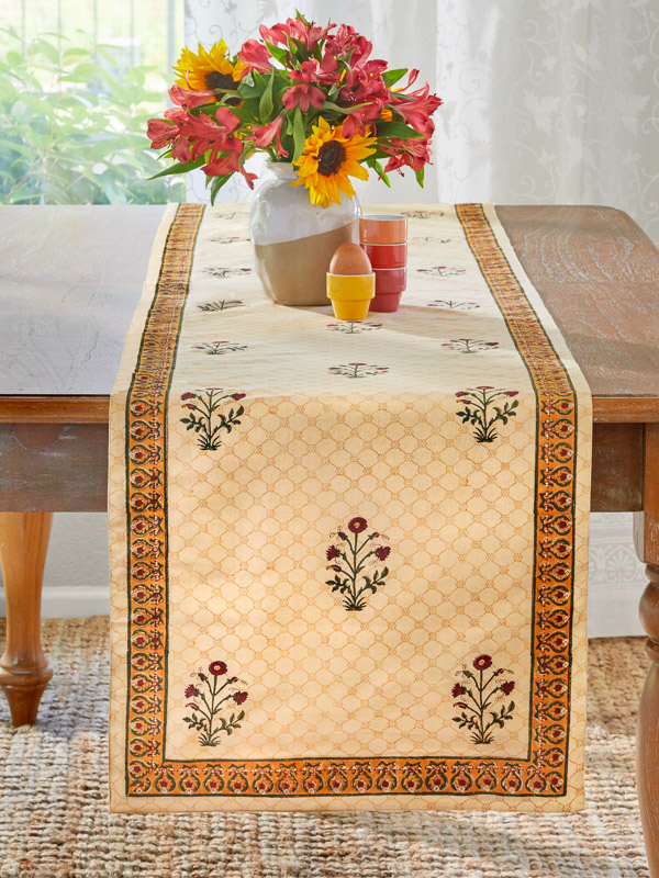 red floral pattern table runner with floral centerpiece and sunflowers in a sunny dining room