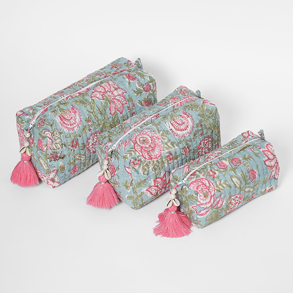 Photograph of a toiletry makeup bag set of three showcasing a pink and green floral print patterned on soft teal with a pink zipper tassel