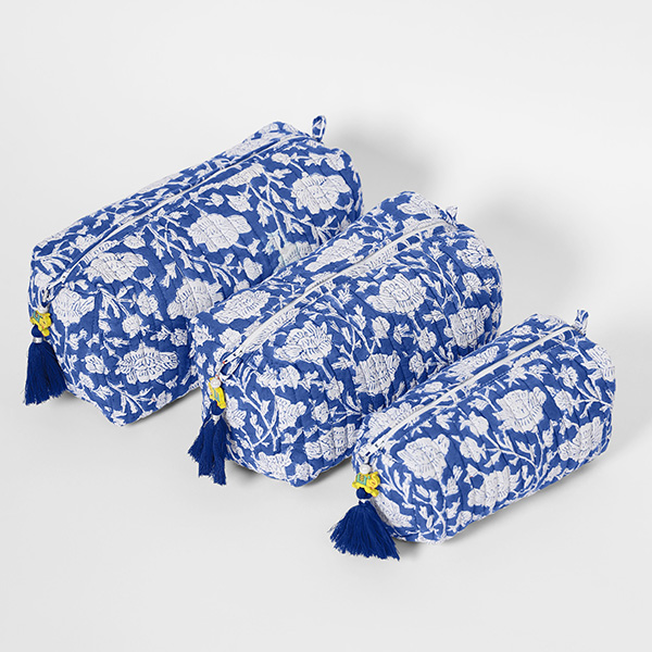 Photograph of a blue and white floral toiletry makeup bag set of three on a background of gray white