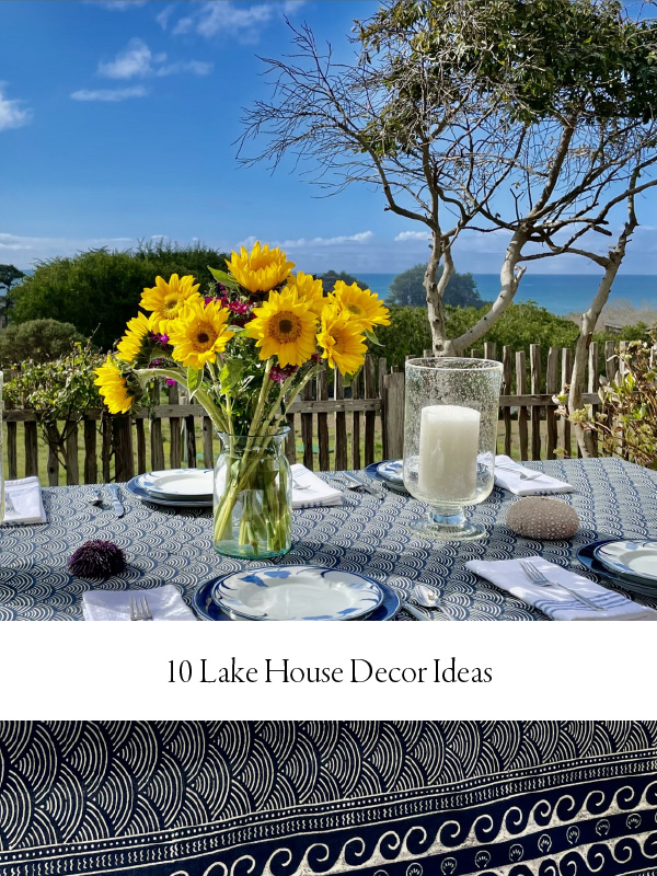 Photograph of a tablescape featuring a navy blue ocean-inspired table linens and a bouquet of sunflowers for a centerpiece to demonstrate lake house decor ideas. In the background is the blue shore and blue sun.