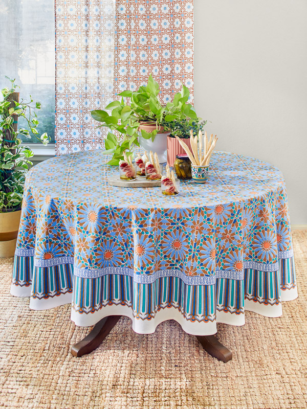 Photograph of a round table covered in a boho tablecloth with overgrown plants and various appetizers arranged above to showcase round table decor