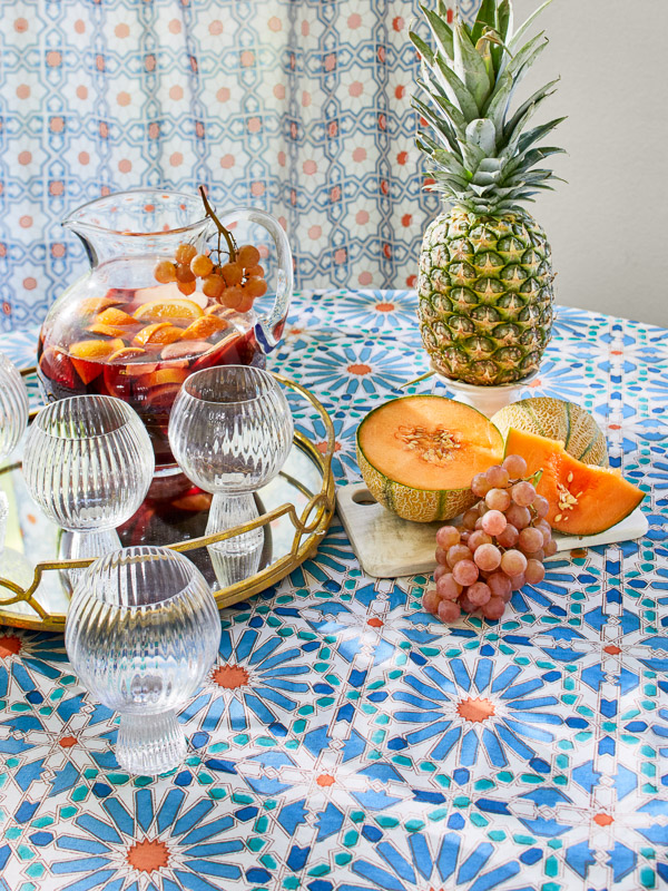 Photograph of round table decor featuring glass goblets and a serving tray with assorted cut fruits