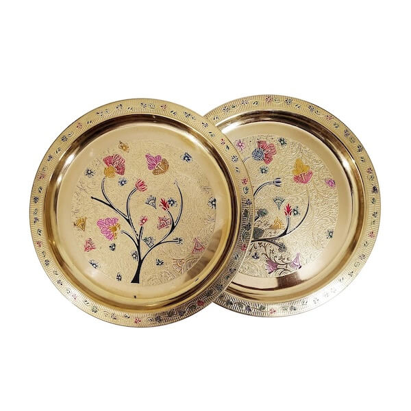 Photograph of two round brass serving trays with floral engravings to demonstrate round table decor ideas