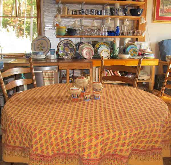 Photograph of an orange and red paisley tablecloth on a round table topped with a decorative tea set to demonstrate round table decor ideas