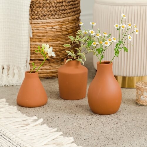 Set of three terra cotta vases to use on sunflower print tablecloth.