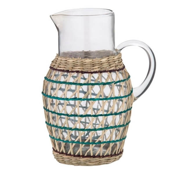 Woven rattan sleeve on glass pitcher for French rustic decor on sunflower print tablecloth.