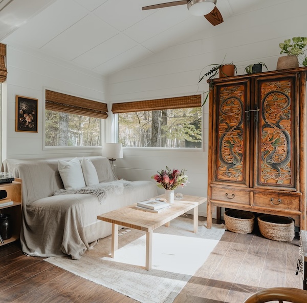 Living room with rustic cabin decor ideas such as an Oriental cabinet, blanket-covered sofa, and woven organizers