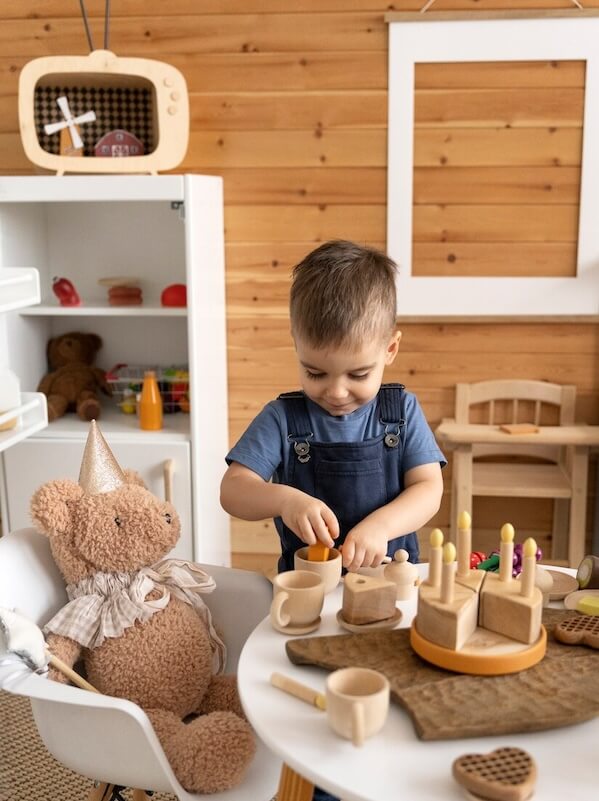 Child playing with wooden kitchen toys in a list of spare room ideas