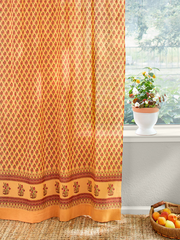 an orange shower curtain with a small red floral pattern and a red floral motif at the border